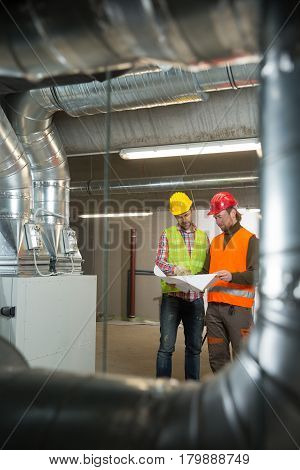Workers making final touches to HVAC system. HVAC system stands for heating, ventilation and air conditioning technology. Team work, HVAC, indoor environmental comfort concept photo.