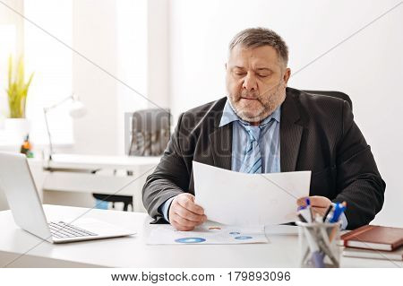 Just look what we have here. Tired overloaded sweaty office worker looking stressed while sitting at his desk and sorting out his correspondence