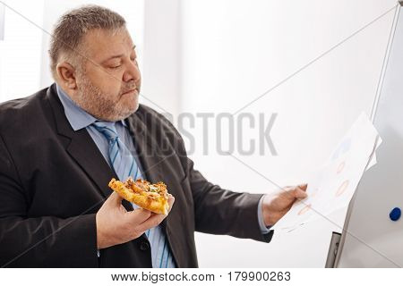 Making it in time. Persistent laborious attentive expert combining his work and midday meal while trying completing his task before deadline