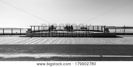 Sitting on benches facing the ocean in the embankment of Les Sables d'Olonne, France