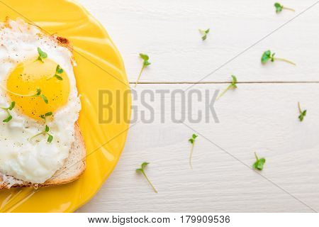 Toast With Egg In Yellow Plate With Micro-greenery On White Wooden Background. Healthy Breakfast. To