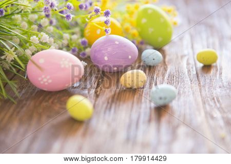 Easter Eggs With Wildflowers On Brown Wooden Background.