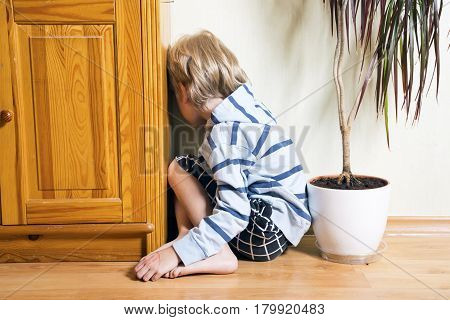 Sad cute little blonde boy turned away
