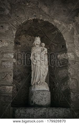 Statue of virgin Mary with stoned background. White stone statue of Saint Mary. Virgin Mary and baby Jesus. Jesus Christ and saint Mary sculpture.