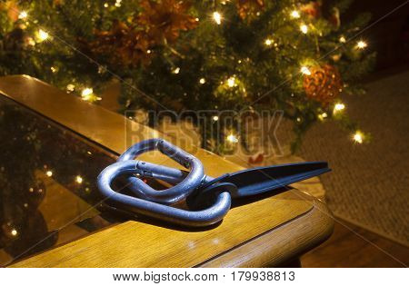 Piton and carabiners on a table next to a lit Christmas tree