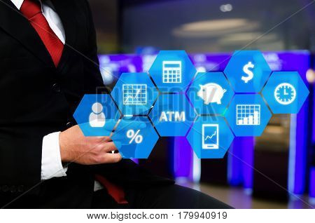 businessman in suit and red necktie using smart phone with finance icon financial technology and business concept on abstract blurred background of ATM Machine for withdraw or deposit cash money.