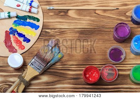Artist's workshop.Items for children's creativity on a wooden background. Acrylic paint and brushes on white wooden background. Picture with copy space and for add text. some art stuff on wooden table