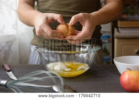 Close-up of woman's hands breaking egg during cooking