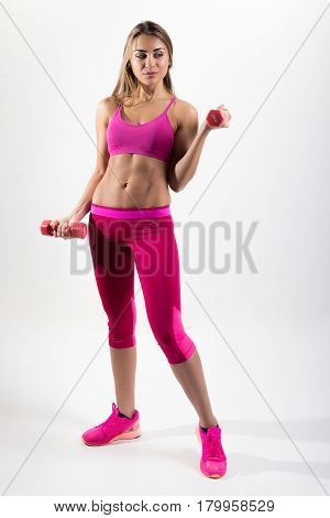 Woman In Sportswear Is Engaged In Fitness. In The Hands Holding Dumbbells. Photo Studio.