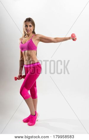 Woman In Sportswear Is Engaged In Fitness. In The Hands Holding Dumbbells. Photo Studio.
