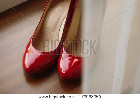 Stylish red women's shoes on wooden floor elegant bride's shoes closeup on rustic background morning wedding preparation