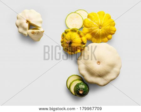 Yellow, white and green zucchini, courgette and round pattipan squashes on blue background. Sorts of cucurbit top view
