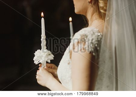 Spiritual couple bride and groom holding candles during wedding ceremony in christian church emotional moment during ceremony woman's hand closeup