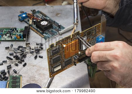 Solder soldering solder integrated circuit. Hand of a soldering soldier with soldering iron. An employee at an electric service while at work.