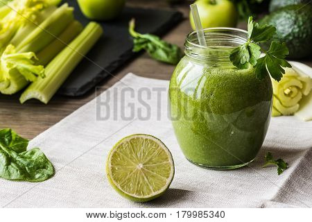 Detox diet. Green smoothie with different vegetables on wooden background.