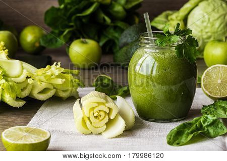 Detox diet. Green smoothie with different vegetables on wooden background.
