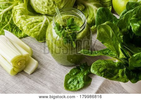 Detox diet. Green smoothie with different vegetables on wooden background.