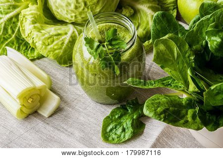 Detox diet. Green smoothie with different vegetables on wooden background.