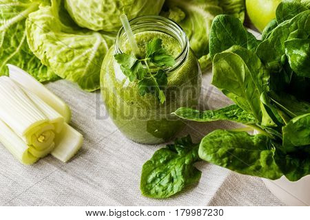 Detox diet. Green smoothie with different vegetables on wooden background.