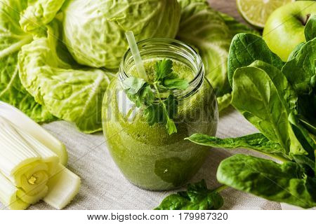 Detox diet. Green smoothie with different vegetables on wooden background.