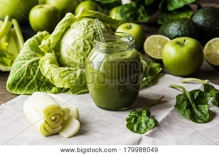 Detox diet. Green smoothie with different vegetables on wooden background.