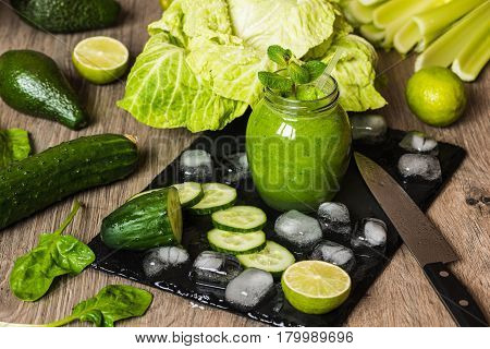 Detox diet. Green smoothie with different vegetables on wooden background.