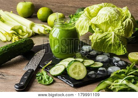 Detox diet. Green smoothie with different vegetables on wooden background.