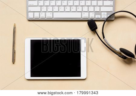 call center manager work desk with tablet and headset on beige background top view