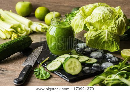 Detox diet. Green smoothie with different vegetables on wooden background.