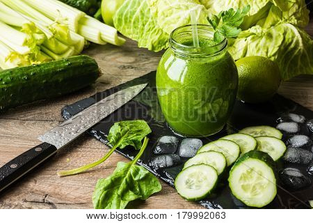 Detox diet. Green smoothie with different vegetables on wooden background.