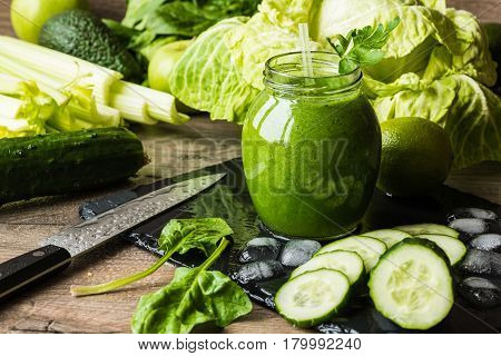 Detox diet. Green smoothie with different vegetables on wooden background.