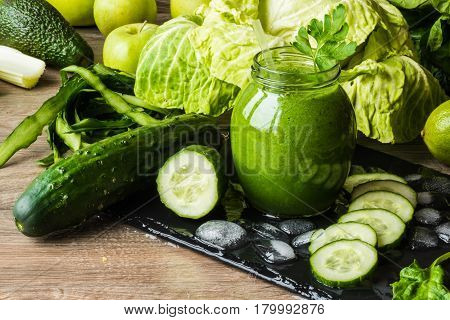 Detox diet. Green smoothie with different vegetables on wooden background.