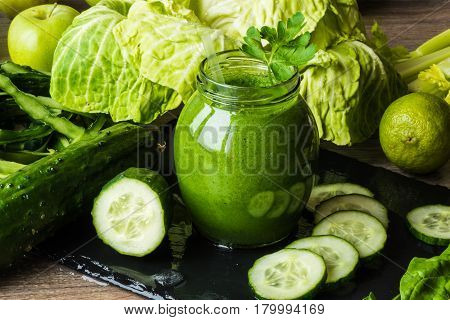 Detox diet. Green smoothie with different vegetables on wooden background.