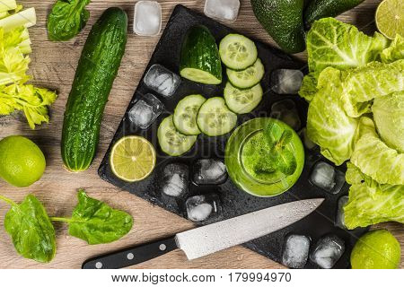 Detox diet. Green smoothie with different vegetables on wooden background.