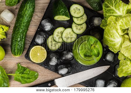 Detox diet. Green smoothie with different vegetables on wooden background.