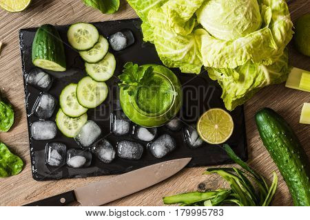 Detox diet. Green smoothie with different vegetables on wooden background.