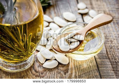 natural oils concept with pumpkin seeds and glass jar on wooden table background