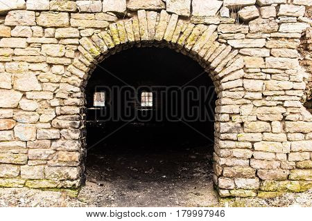 Opening in the wall made in the form of an arch. Limestone carpentry walls. A window with a lattice in the depths.