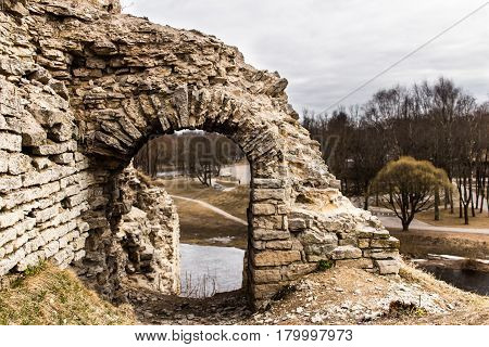 Ruins of medieval defensive structures against the background of the river and the park.