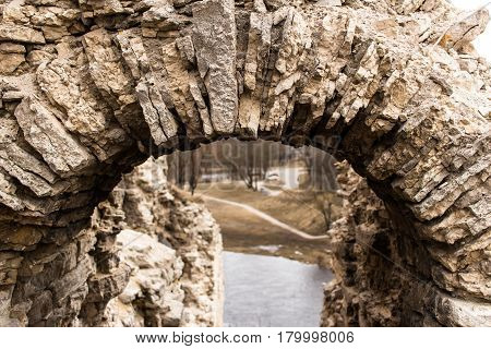 A fragment of a stone arch from limestone. Ruins of a medieval Russian fortress. Remains of the entrance to the tower.