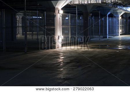 Empty Poorly Illuminated Coridor In Underground Parking Garage With Separate Boxes, Horror