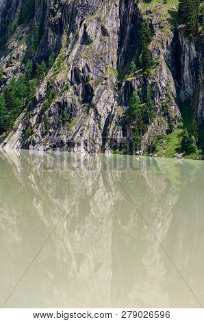 Summer Alps Mountain Landscape With Turbid Water Reservoir Lake And Steep Rocky Slopes, Switzerland