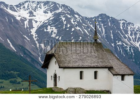 Lovely Small Old Church In Bettmeralp Alps Mountain Village, Switzerland. Summer Cloudy View.