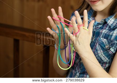 Child playing classic, old-school string game and didactic toy with her fingers, creating shapes, developing her motor skills. IQ, education, intelligence, fun and childhood concept.