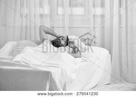 Man In Shirt Laying On Bed Awake, White Curtain On Background. Guy On Disappointed Painful Face Waki