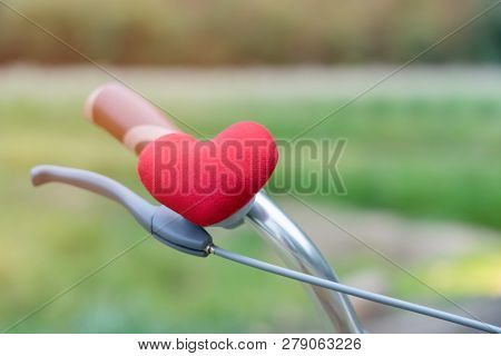 A Little Red Heart Pillow On The Bicycle Handlebar.