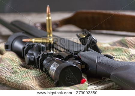 The Ammo With Black Bolt Action Rifle And Scope On The Multicam Background. Close Up.