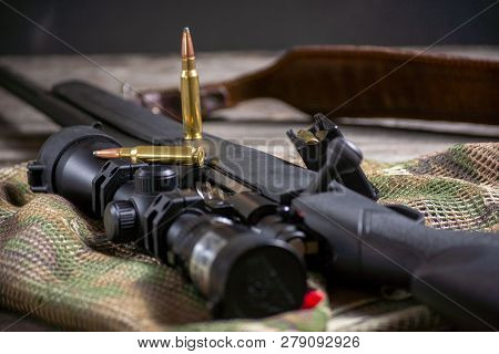 The Ammo With Black Bolt Action Rifle And Scope On The Multicam Background. Close Up.