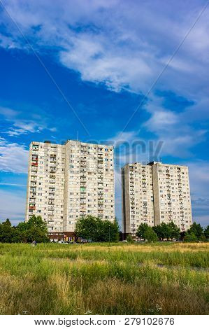 Poznan, Poland - July 10, 2018: Two Old High Apartment Blocks Behind Green Grass And Trees On The Or