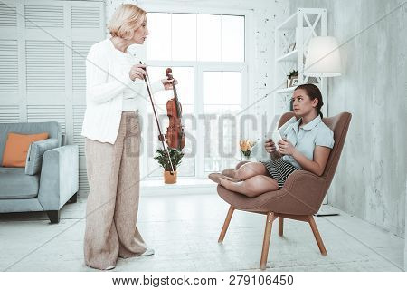 Cheerless Blonde Woman Making Her Granddaughter Play Violin